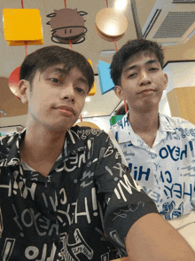 two young men are posing for a picture with one wearing a shirt that says " hey " on it