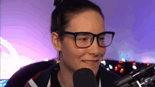 a woman wearing glasses and earrings is talking into a microphone .