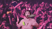 a shirtless man with headphones is dancing in front of a crowd of people with their hands in the air