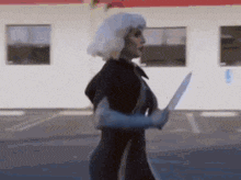 a woman in a wet suit is holding a knife in a parking lot