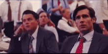 a group of men in suits and ties are sitting in a row in a room .