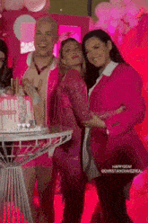 a group of people standing next to each other in front of a cake .