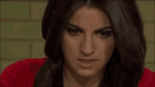 the woman is wearing a red shirt and making a funny face .