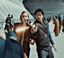 a man is pointing a gun at a woman who is holding a light .