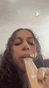 a woman is eating a yellow candy bar with a sticker on her head