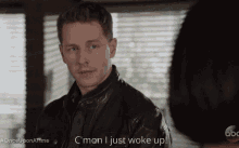 a man in a leather jacket is talking to a woman and says " c'mon i just woke up " .