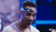a man wearing a headband with a comb on it and a bet logo in the background