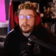 a man with a beard and glasses is wearing headphones and a microphone .