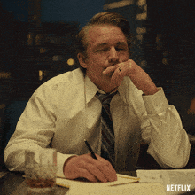 a man in a white shirt and tie sits at a desk with netflix written on the bottom