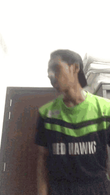 a man wearing a green and black seattle seahawks jersey is standing in front of a door .