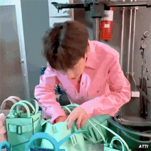 a man in a pink shirt is holding a green bag