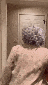a woman with purple hair is standing in a hallway .