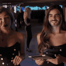 a man with a beard is standing next to a woman who is covering her mouth with her hand