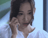a woman in a white shirt is talking on a cellphone