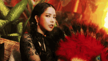 a woman in a black dress is sitting on a couch holding a red fan