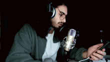 a man wearing headphones is singing into a microphone while holding a cell phone