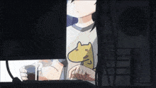 a person with a cat on their shirt is looking out a window at night .