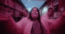 a woman in a pink jacket is taking a selfie with her friends in a pink room .