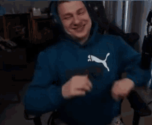 a man wearing headphones and a blue hoodie is sitting in a chair and dancing .