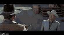 a man in a suit and cowboy hat is talking to another man