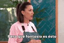 a woman in a pink shirt and blue apron says pero qué fantasia es esta