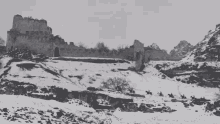 a black and white photo of a snowy mountain with a castle in the background