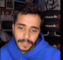 a man with a beard is wearing a blue sweatshirt with the word issoia on it .