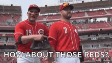 two baseball players in red uniforms are standing next to each other in a stadium .
