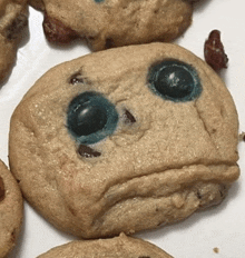 a close up of a cookie with blue eyes and a sad face