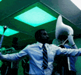 a man in a blue shirt and tie is holding up a horn