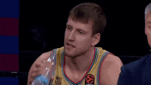 a close up of a man wearing a basketball jersey making a face
