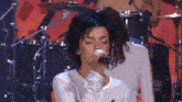 a woman singing into a microphone with a nbc logo in the corner