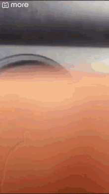 a close up of a person 's face with a blurred background and the word more on the bottom .