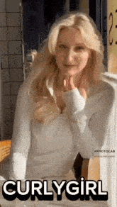 a woman with blonde hair is sitting at a table with the words curlygirl on the bottom