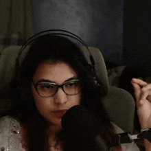 a woman wearing glasses and headphones is sitting in front of a microphone