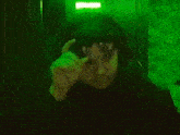 a man wearing headphones and a hat is sitting in a dark room with green lights .