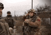 a group of soldiers are standing in a field and one of them is wearing a helmet with the letter r on it
