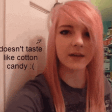a girl with pink hair is taking a selfie in front of a sign that says does n't taste like cotton candy
