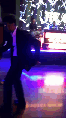 a man in a suit is dancing in front of a screen that says ' x ' on it