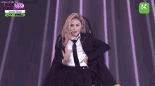 a woman in a suit and tie is dancing on stage