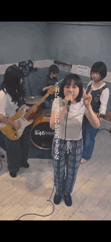 a girl is singing into a microphone in front of a drum that says 246 on it