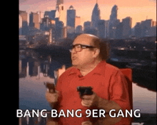 a man in a red shirt is holding a gun in front of a city skyline and says bang bang 9er gang .