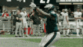 a football player catches a pass on a field with the number 27 in the background