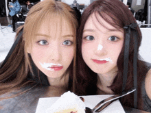 two girls with frosting on their faces and a piece of cake