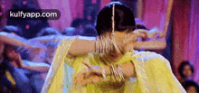 a woman in a yellow dress is dancing in front of a crowd in a room .