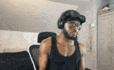 a man wearing headphones and a headband is sitting in a chair in a room .