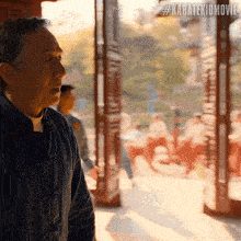 a man in a blue jacket is standing in front of a window with a sign that says #karatekidmovie on it