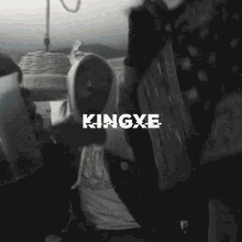a man in a hooded sweatshirt is holding a bag of money in front of a sign that says kingxe