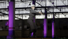 a person wearing a helmet is standing in a warehouse with purple lights