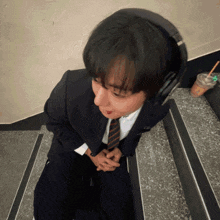 a man wearing headphones sits on a set of stairs next to a cup of coffee